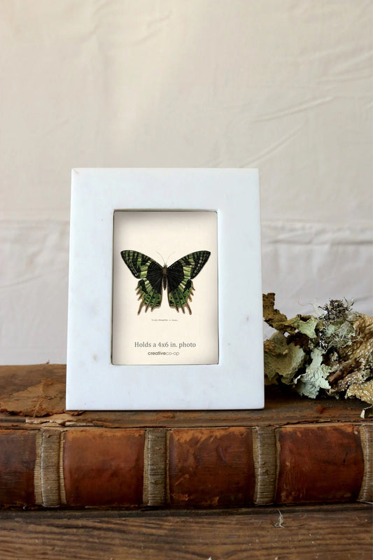 white marble picture frame on wood with butterfly in the image